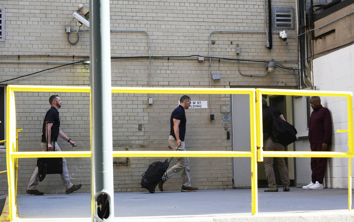 FBI agents walk inside the back entrance of the Washington office of ex-Trump national security ...