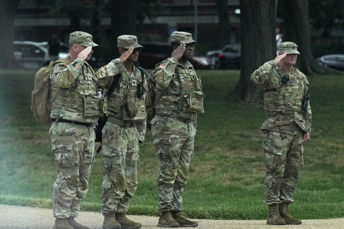 National Guard soldiers salute as the motorcade carrying President Donald Trump, passes by near ...
