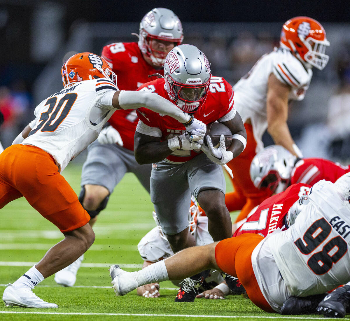 UNLV running back Jaylon Glover (20) blasts his way through the line Idaho State Bengals corner ...