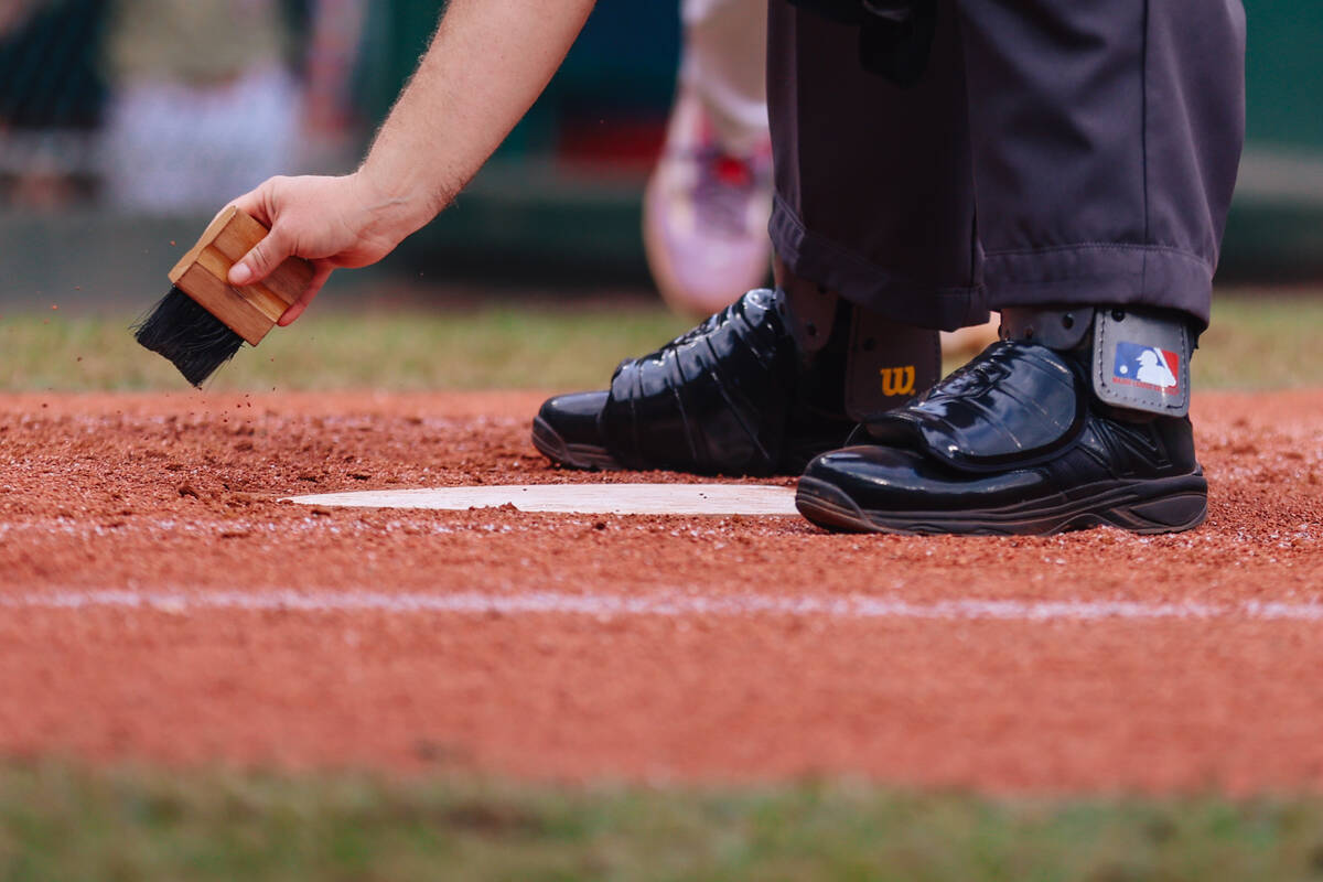 An umpire cleans the home plate during a Little League World Series semifinals game between Sum ...