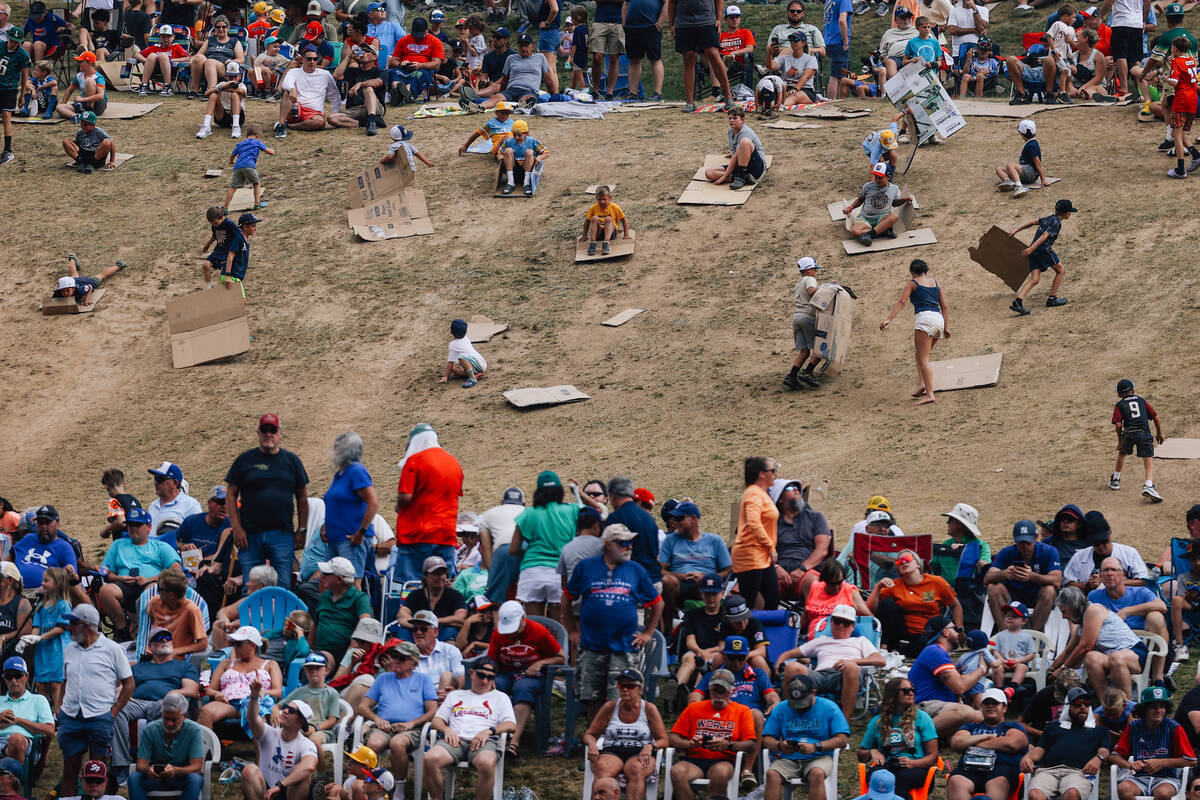 People slide down a hill on cardboard strips during a Little League World Series semifinals gam ...