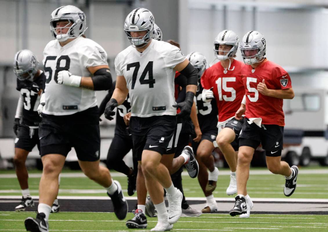 Raiders backup quarterbacks Kenny Pickett (15) and Cam Miller (5) warm up during team practice ...