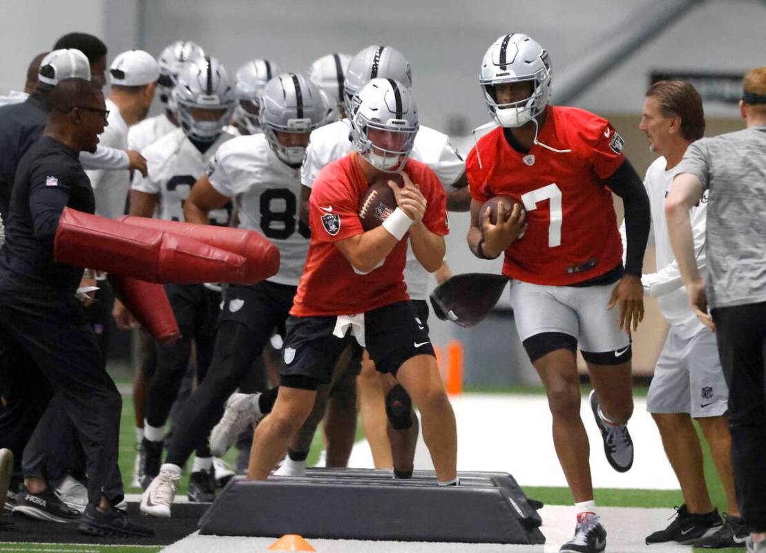 Raiders quarterbacks Geno Smith (7) and Cam Miller (5) work on drills during practice at the In ...