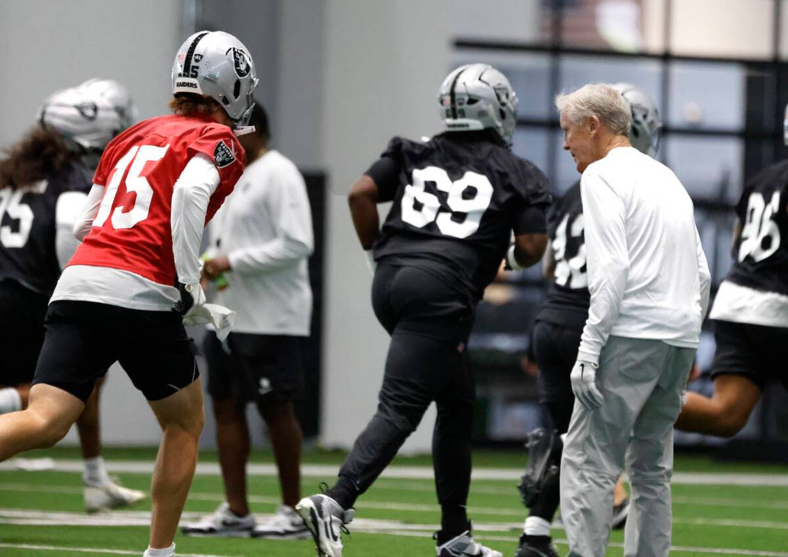 Raiders head coach Pete Carroll watches as backup quarterback Kenny Pickett (15) warms up durin ...