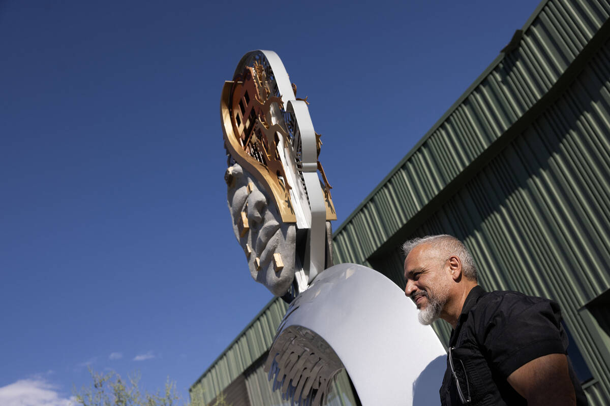 Artist Adolfo Gonzalez stands next to a sculpture he created during a ribbon cutting ceremony h ...