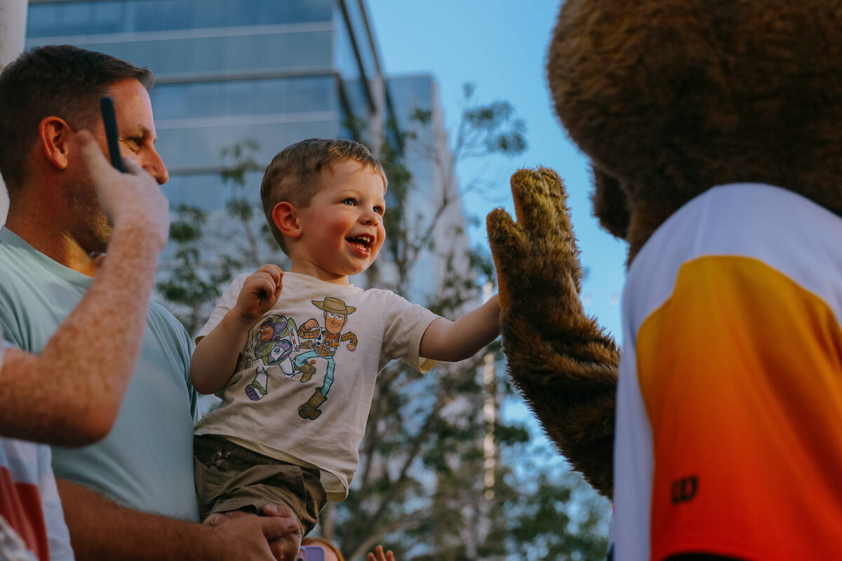 A little boy high fives Summerlin Sam during a parade for the Summerlin South Little League tea ...