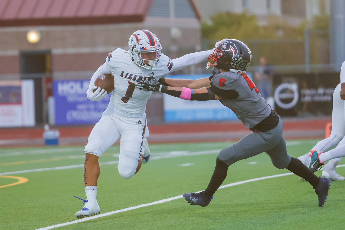 Liberty Running Back Ezra Sanelivi (1) stiff arms Coronado defender during a football game betw ...