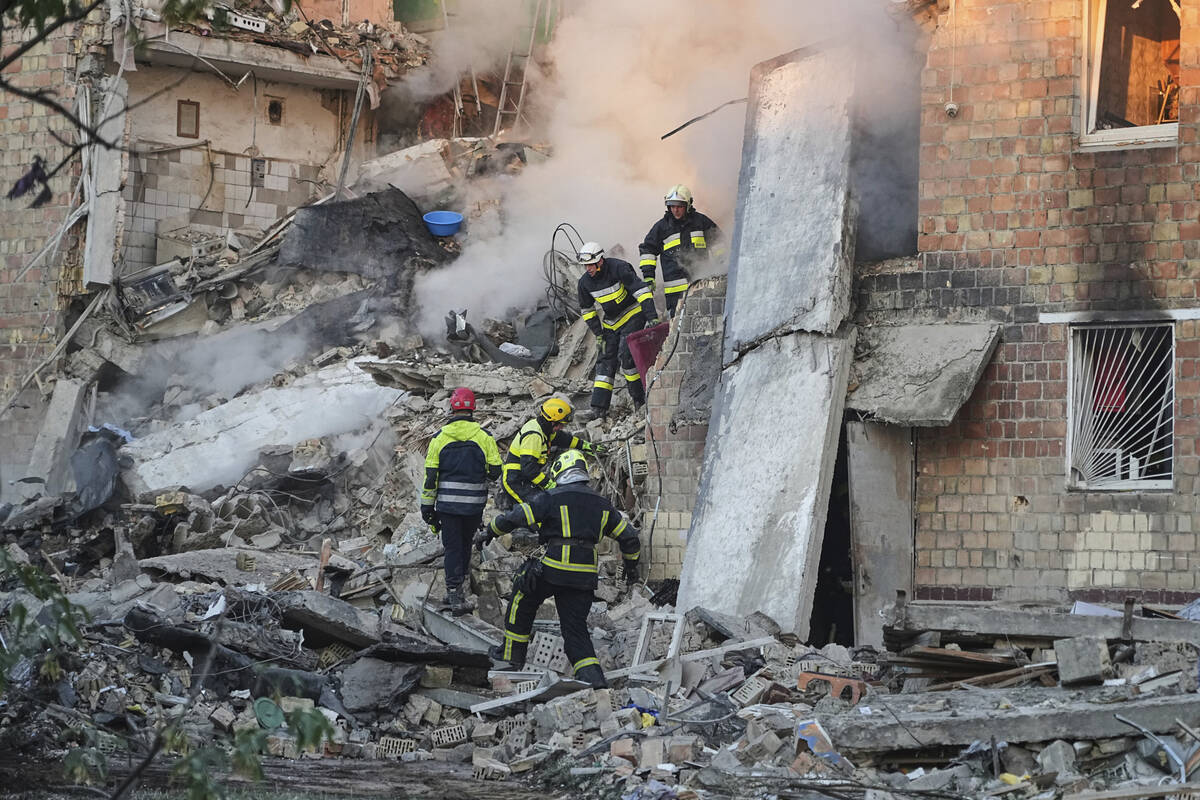 Firefighters work on the site of a burning building after a Russian attack in Kyiv, Ukraine, ea ...