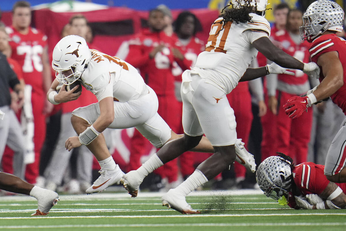 Texas quarterback Arch Manning, left, runs against Ohio State during the first half of the Cott ...