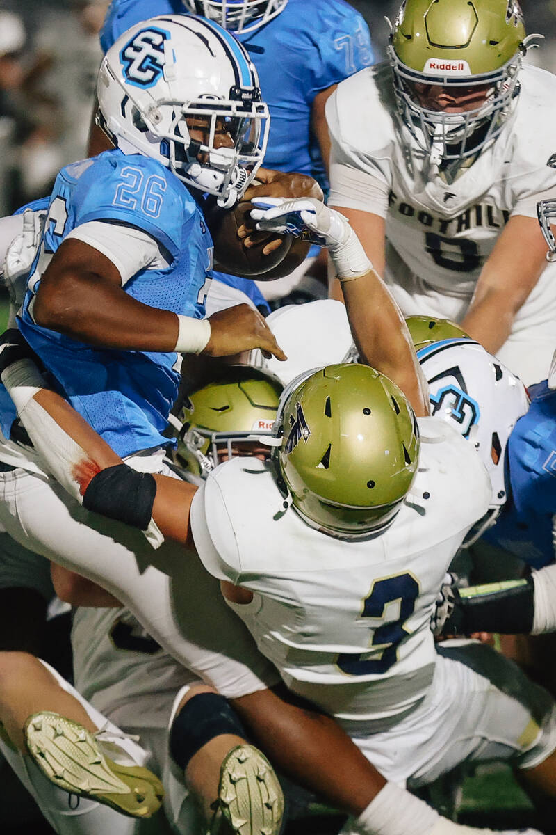 Sloan Canyon running back Cameron Greene (26) gets piled in by defenders during a high school f ...