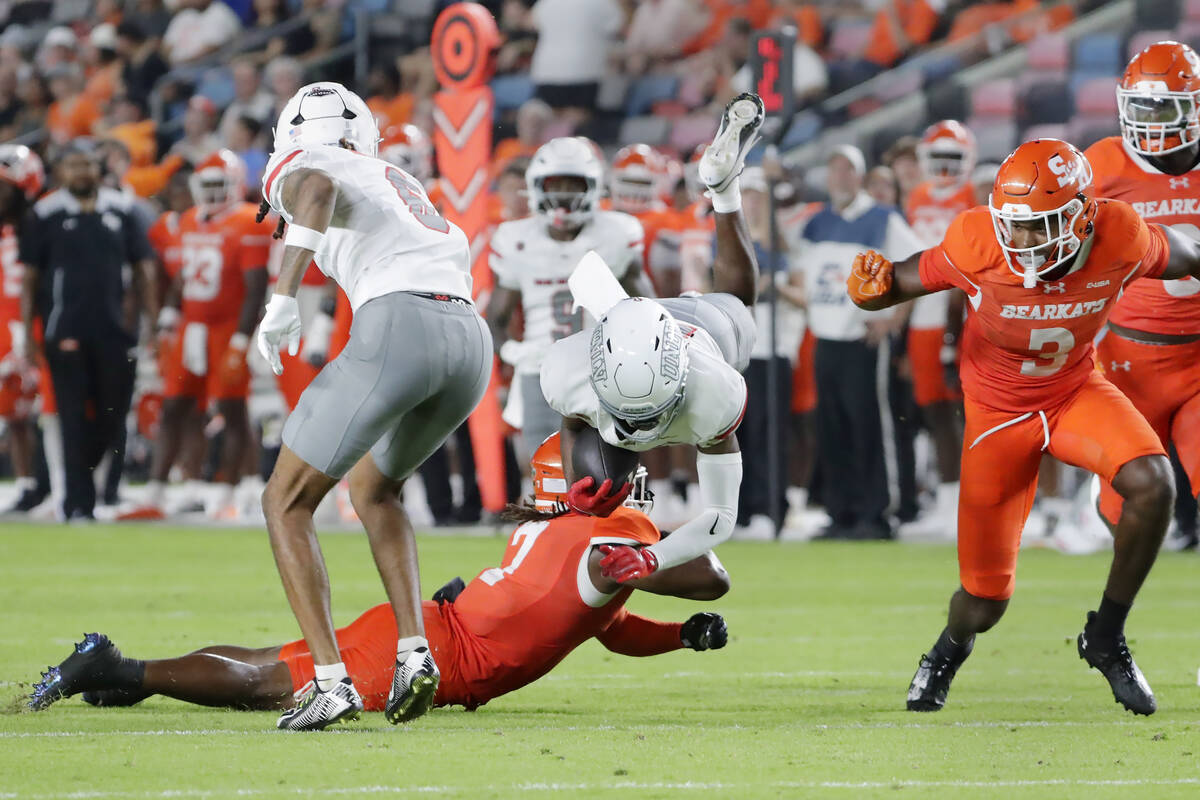 UNLV wide receiver Jojo Earle, center, is upended by Sam Houston State defensive back Emon Alle ...