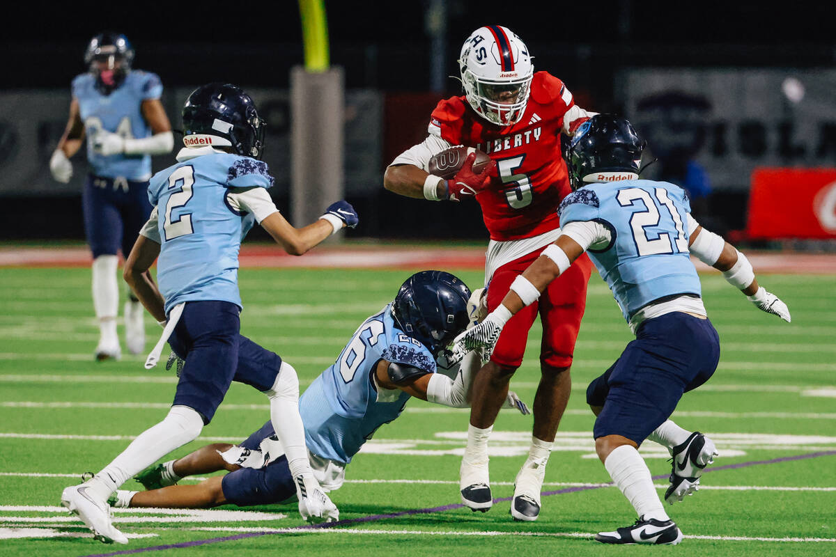 Liberty wide receiver Jashawn Crayton (5) powers through defenders during a high school footbal ...