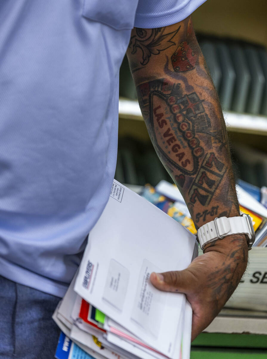 Ishe Smith sorts the mail he will deliver on his route as a mail carrier while starting his shi ...