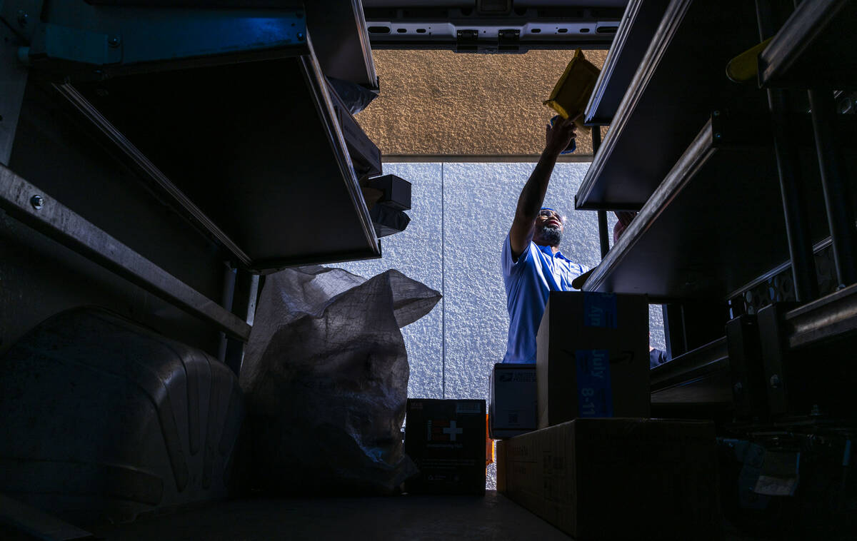 Ishe Smith separates the mail he will deliver on his route as a mail carrier into bins in his t ...