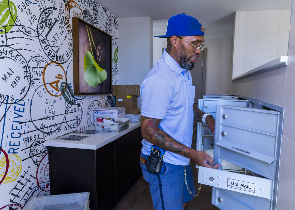 Ishe Smith opens mail slots for resident's mail as he makes an apartment stop along his route a ...