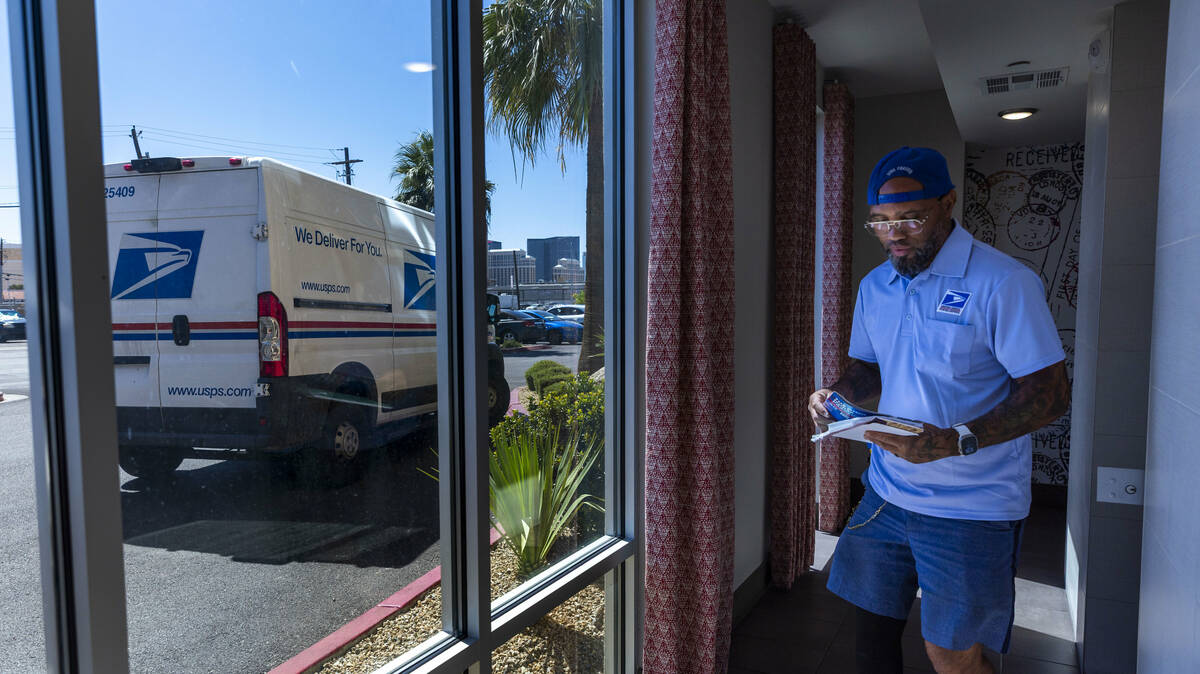 Ishe Smith delivers a resident's mail as he makes an apartment stop along his route as a mail c ...