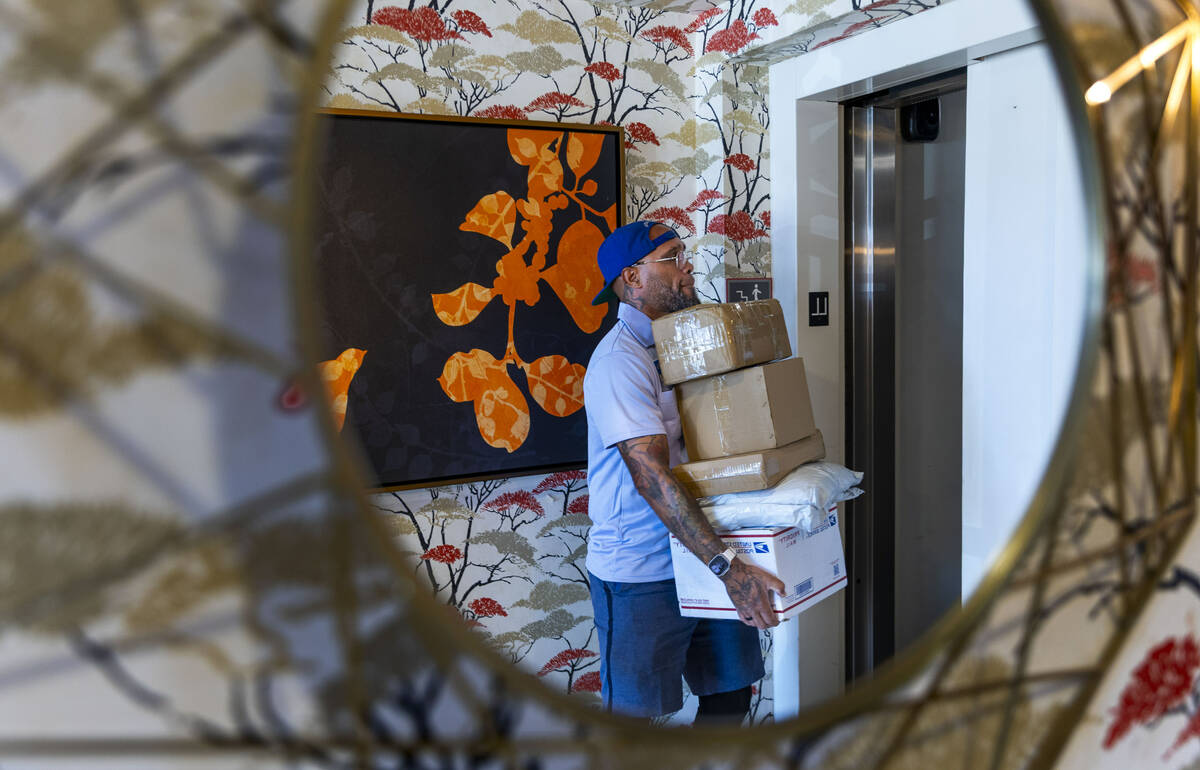 Ishe Smith carries packages upstairs to delivers a resident's mail as he makes an apartment sto ...