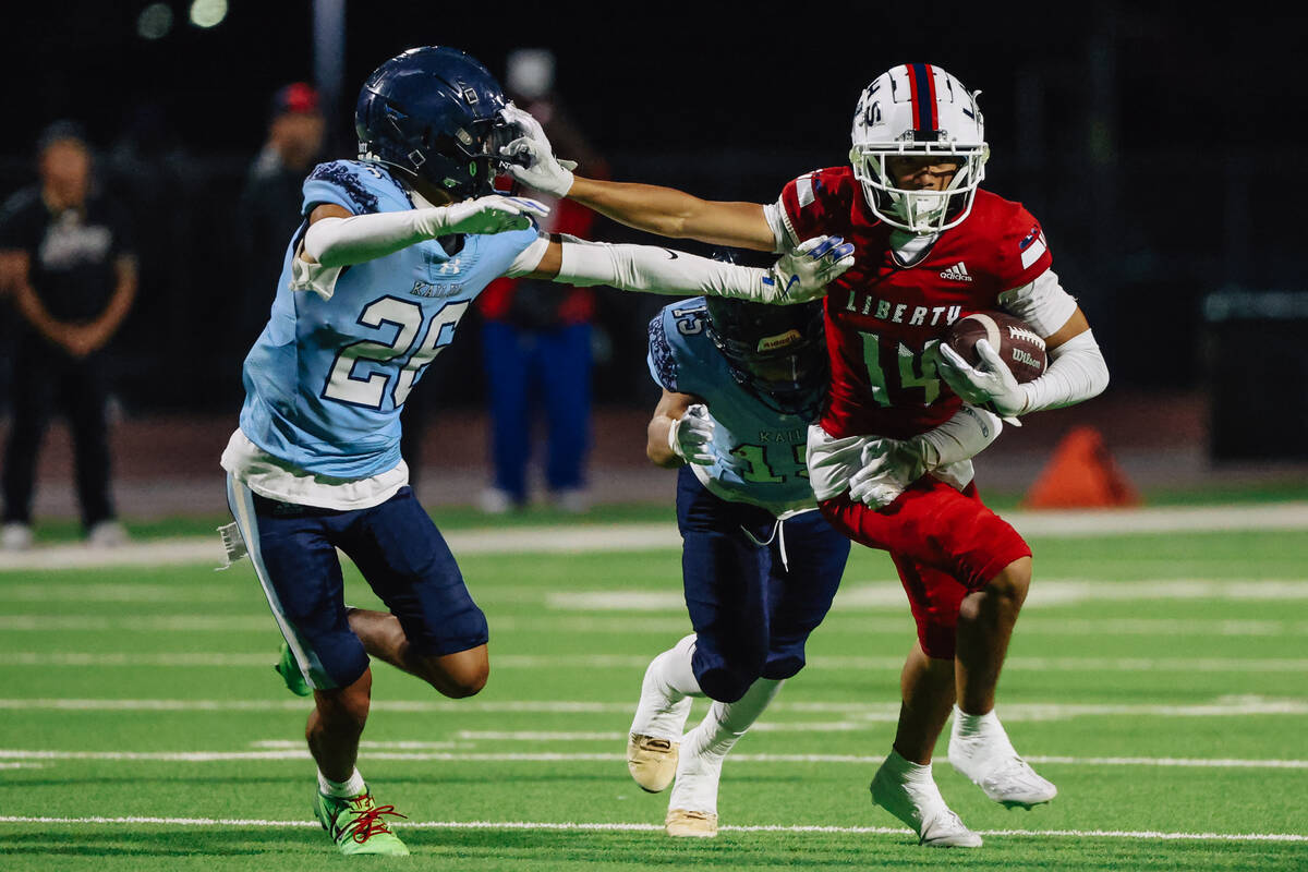 Marley Ganiron (14) carries the ball past his opponents during a high school football game betw ...