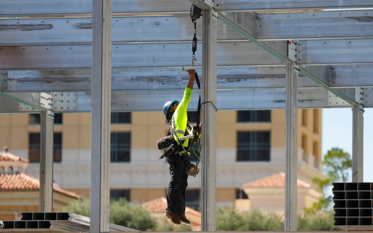A construction worker jumps to secure his safety harness at the Formula 1 construction site at ...