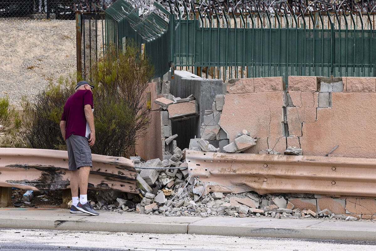 A pedestrian looks at a damaged wall after a fatal crash near the intersection of Charleston Bo ...