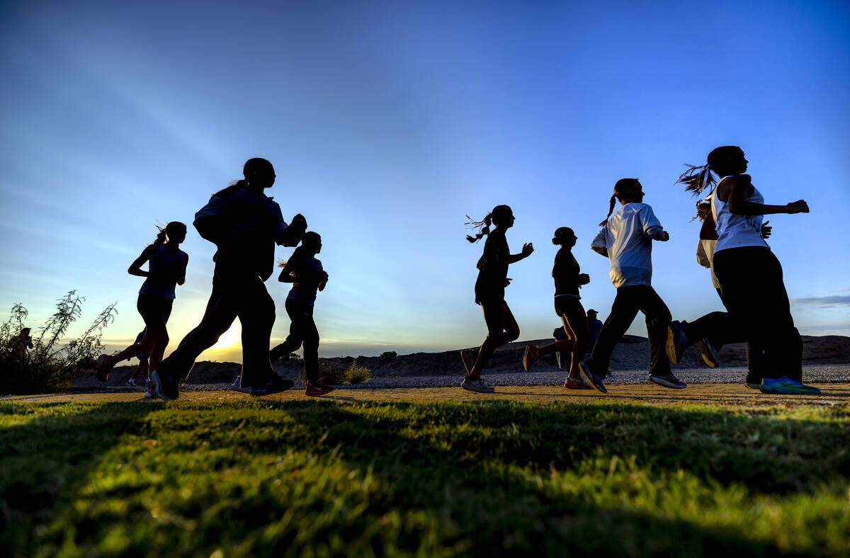 Runners warm up as the sun rises before the first race starts at the 55th Annual Las Vegas/Larr ...