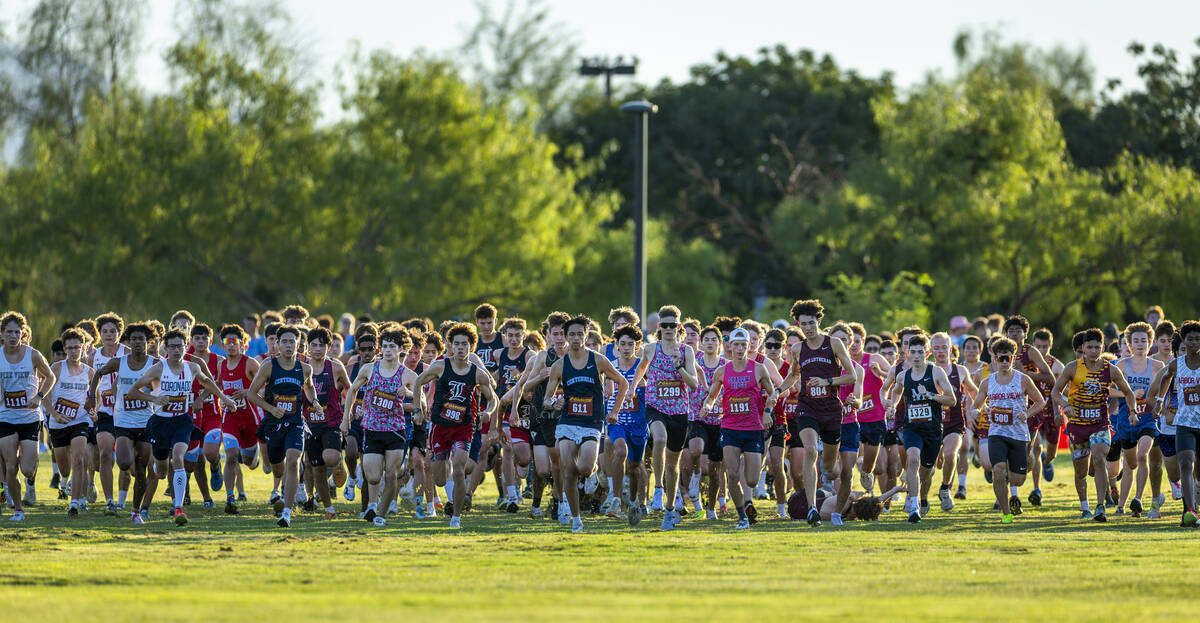 Varsity A Boys competitors blast from the start line as one runner goes down in the pack during ...