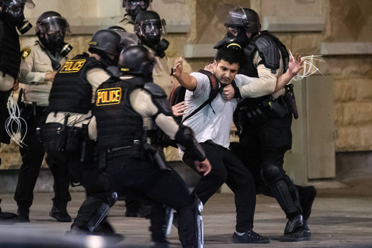 Las Vegas police detain a nonviolent protester before dragging him away on the ground on Wednes ...