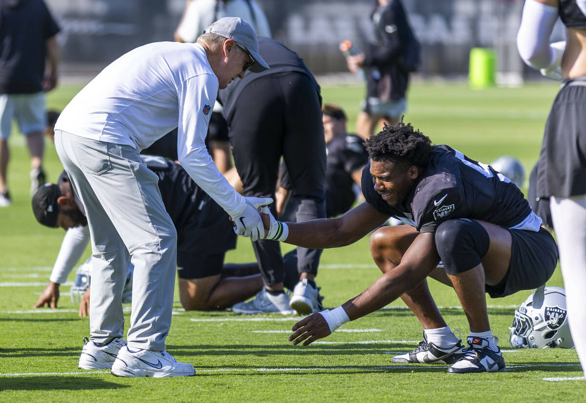 Raiders head coach Pete Carroll greets defensive end Malcolm Koonce (51) as he stretches during ...