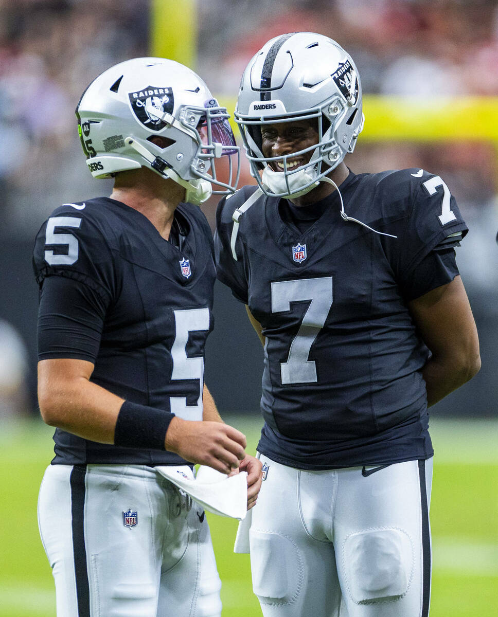 Raiders quarterback Cam Miller (5) chats with quarterback Geno Smith (7) on a timeout against t ...