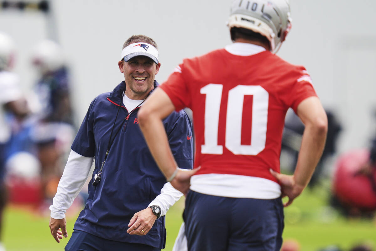 New England Patriots offensive coordinator Josh McDaniels smiles while talking with quarterback ...