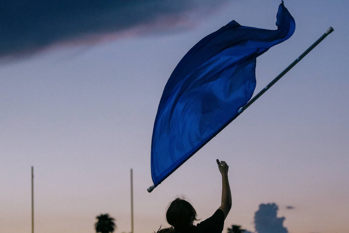 A Green Valley color guard member tosses up a flag while performing with the marching band duri ...