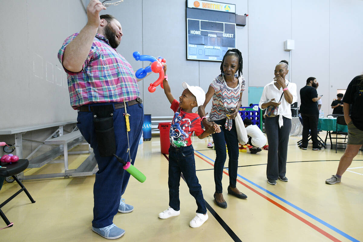 Gwendolyn White holds her grandson Akeem Shepard’s hand as he pretends to attach balloon arti ...