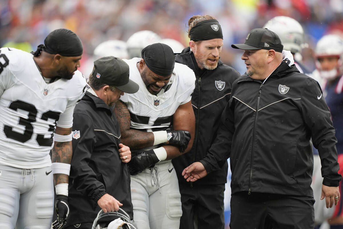 Las Vegas Raiders linebacker Elandon Roberts, center, is helped off the field during the first ...