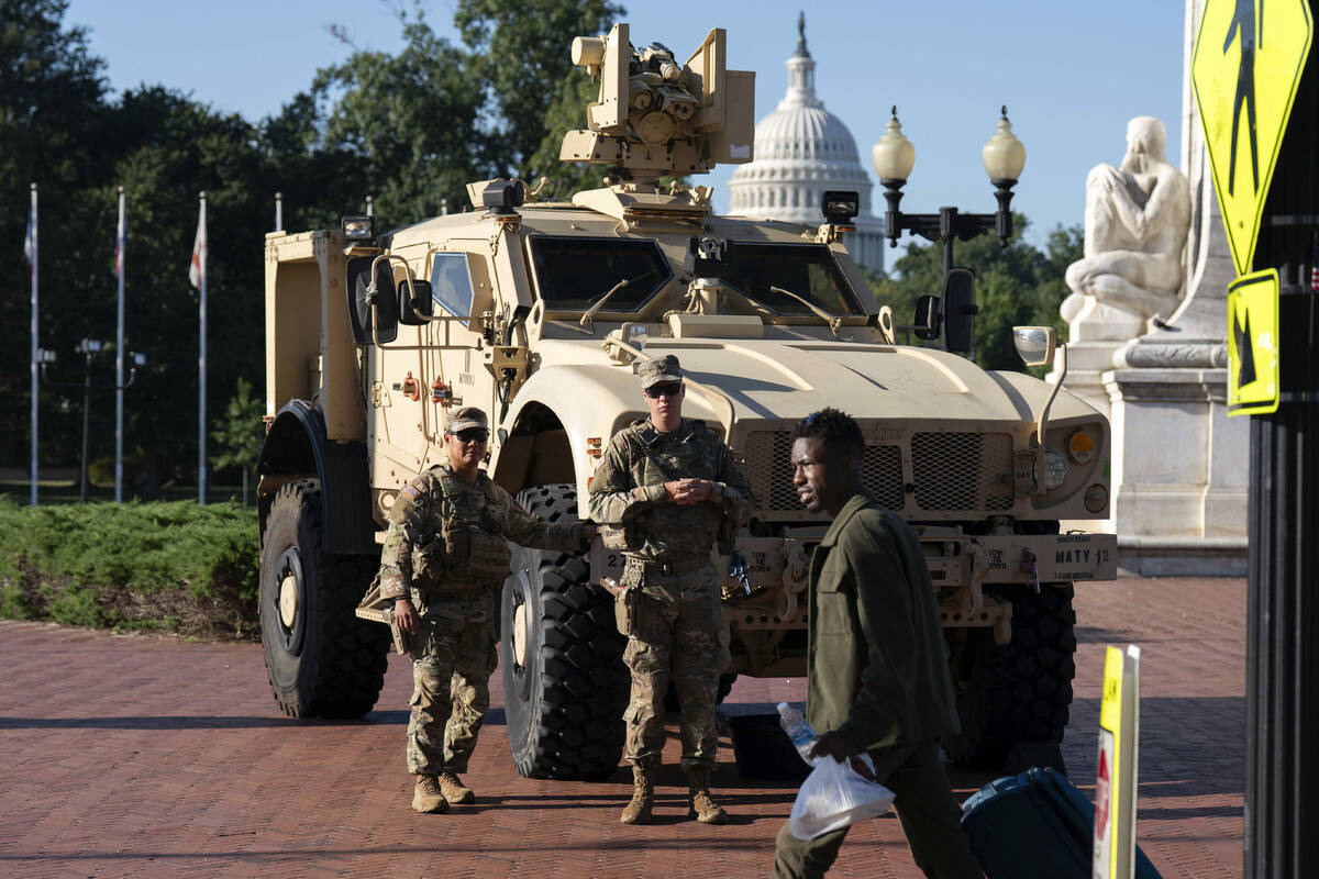 Members of the District of Columbia National Guard standing next to an MATV vehicle scan the ar ...
