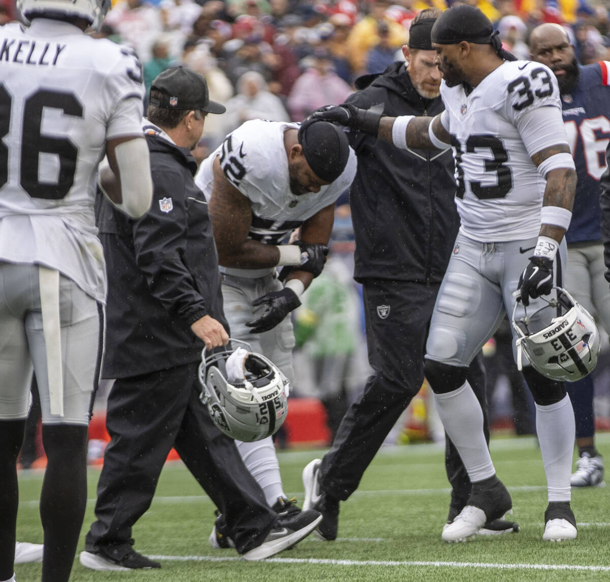 Raiders linebacker Elandon Roberts (52) comes off the field with trainers after suffering an i ...