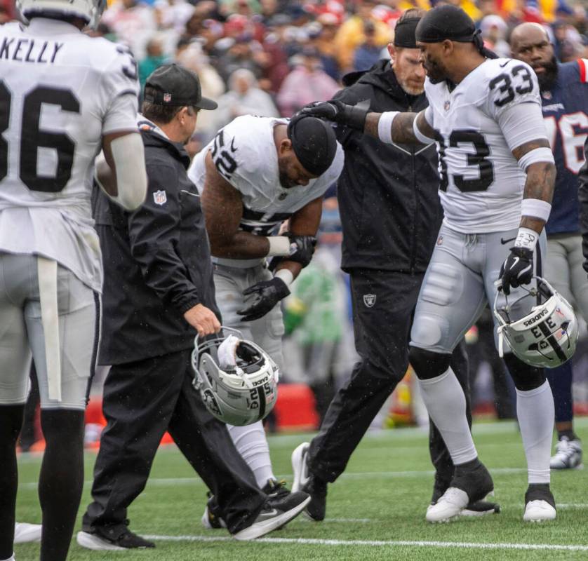 Raiders linebacker Elandon Roberts (52) comes off the field with trainers after suffering an i ...