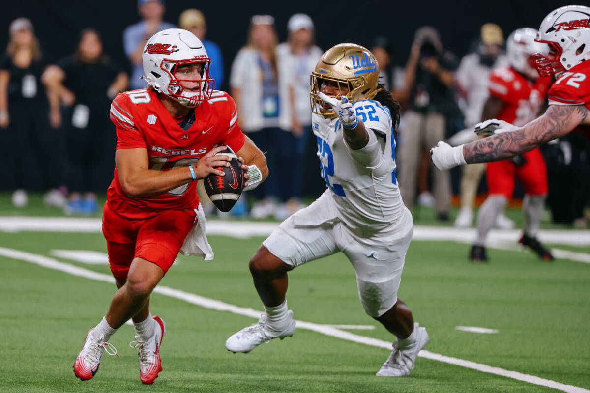 UNLV quarterback Anthony Colandrea (10) looks to run around UCLA defensive lineman Kechaun Benn ...