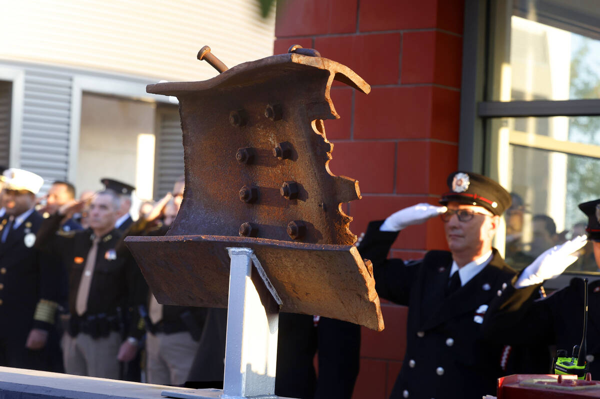 A piece of structural steel from the World Trade Center is displayed as fire fighters salute as ...