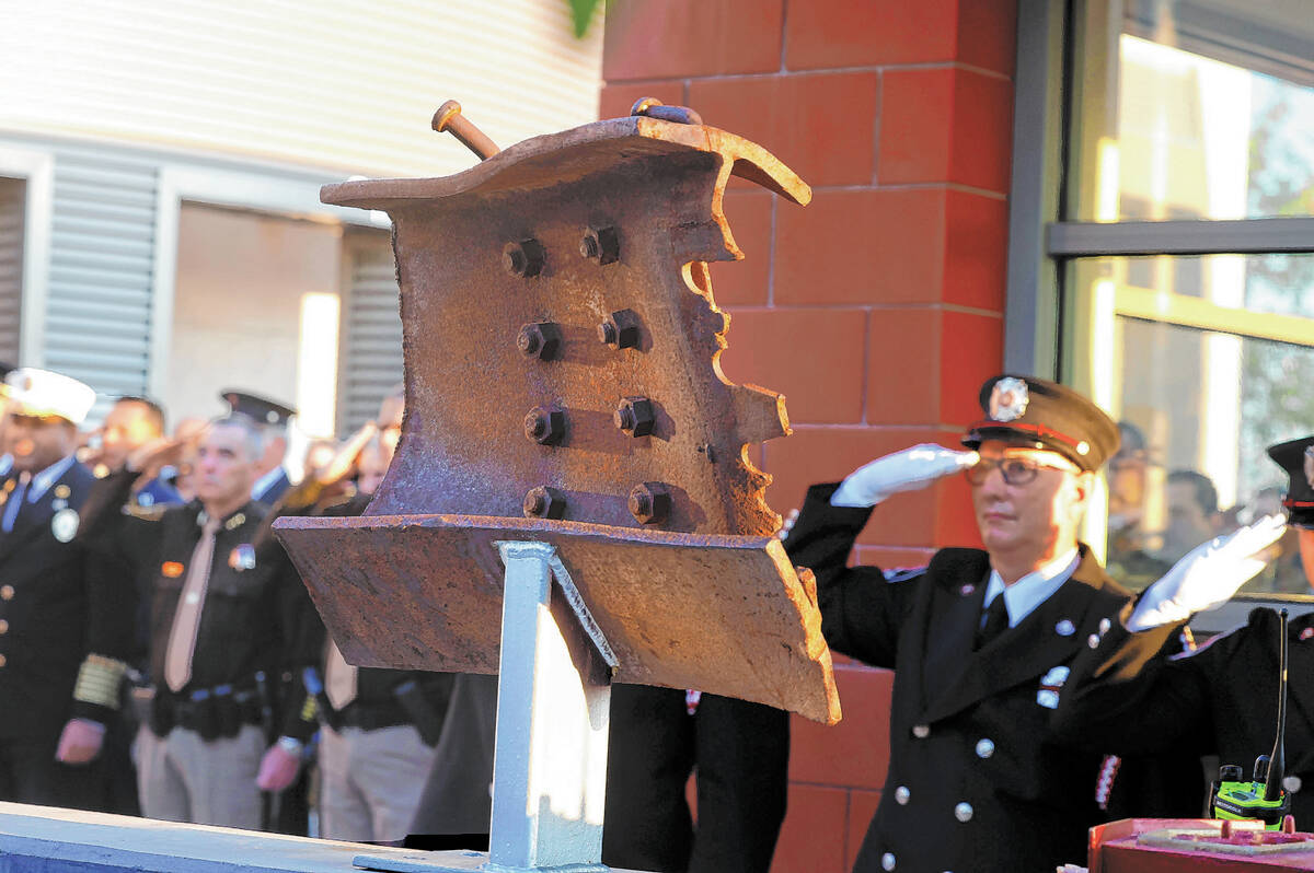 A piece of structural steel from the World Trade Center is displayed as fire fighters salute as ...