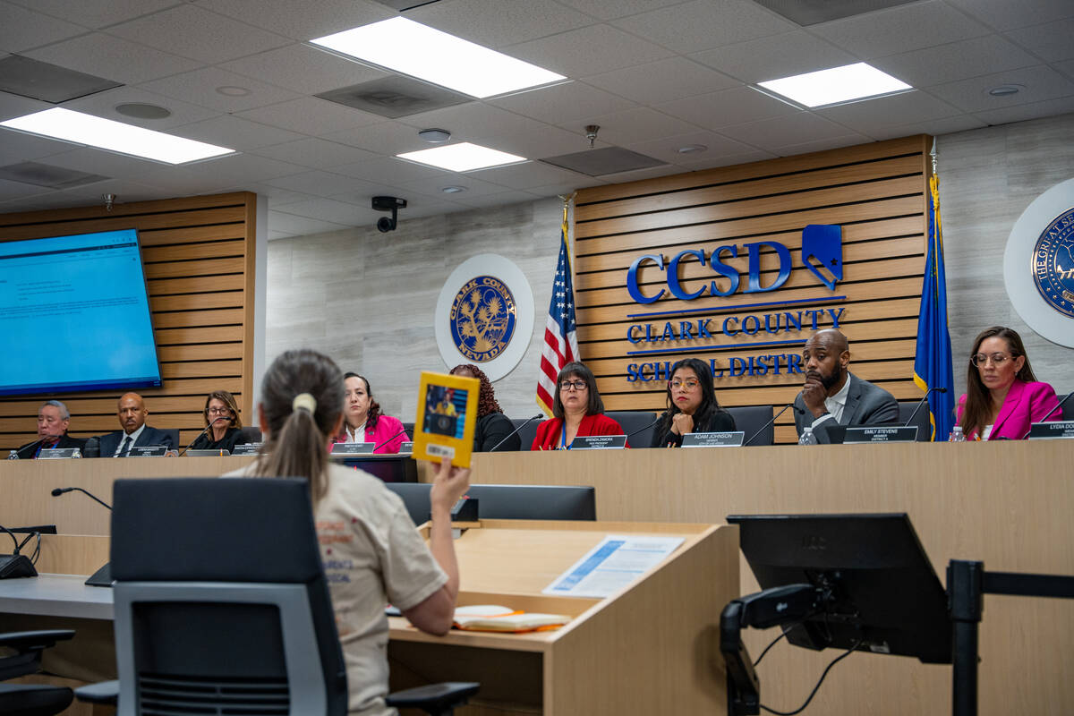 A community member holds up a book during a Clark County School Board meeting at the Edward A. ...