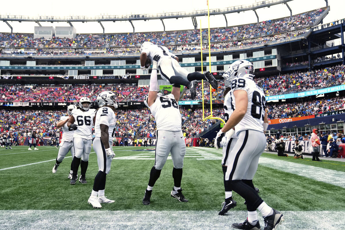 Las Vegas Raiders center Jackson Powers-Johnson (58) holds up Las Vegas Raiders wide receiver T ...