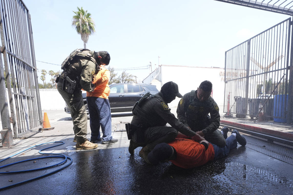 Immigration agents detain two men at a car wash on Friday, Aug. 15, 2025, in Montebello, Calif. ...