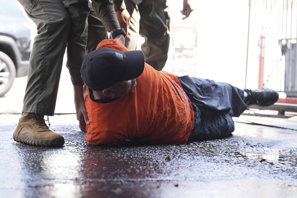 A man is detained by immigration agents at a car wash on Friday, Aug. 15, 2025, in Montebello, ...