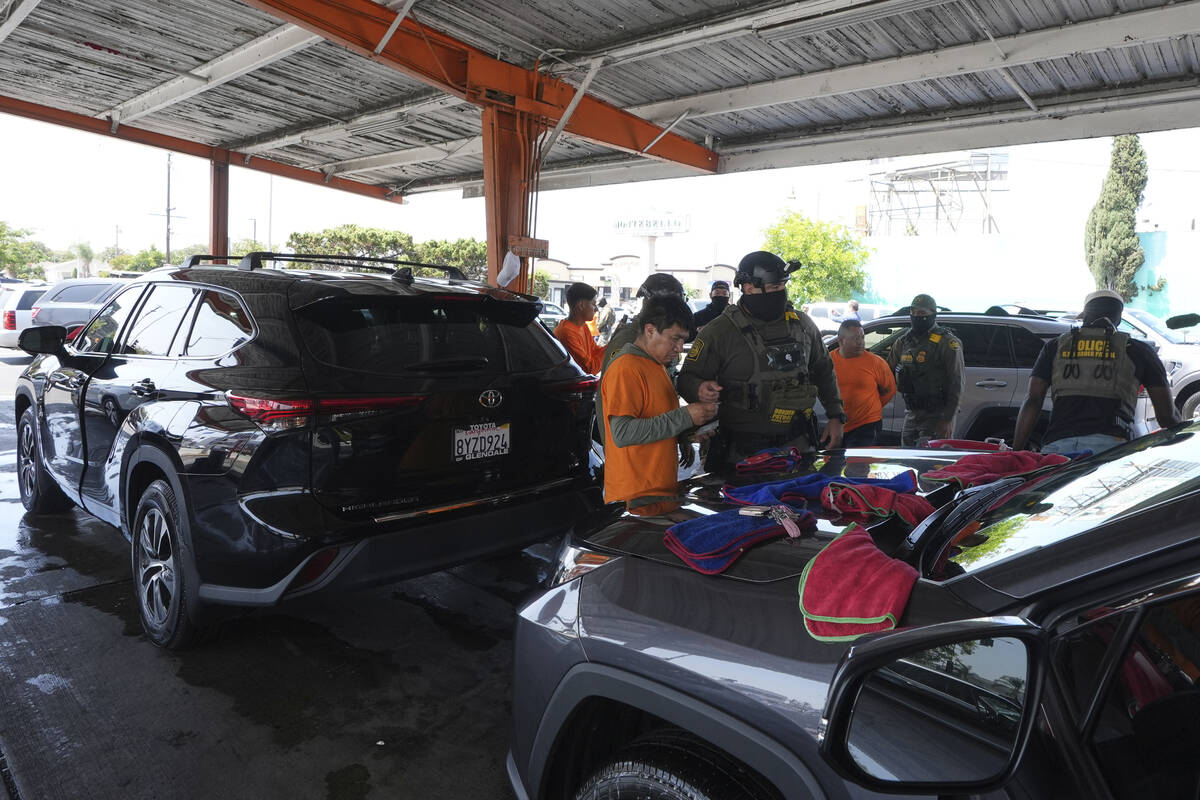 Immigration agents conduct arrests and check identifications at a car wash on Friday, Aug. 15, ...