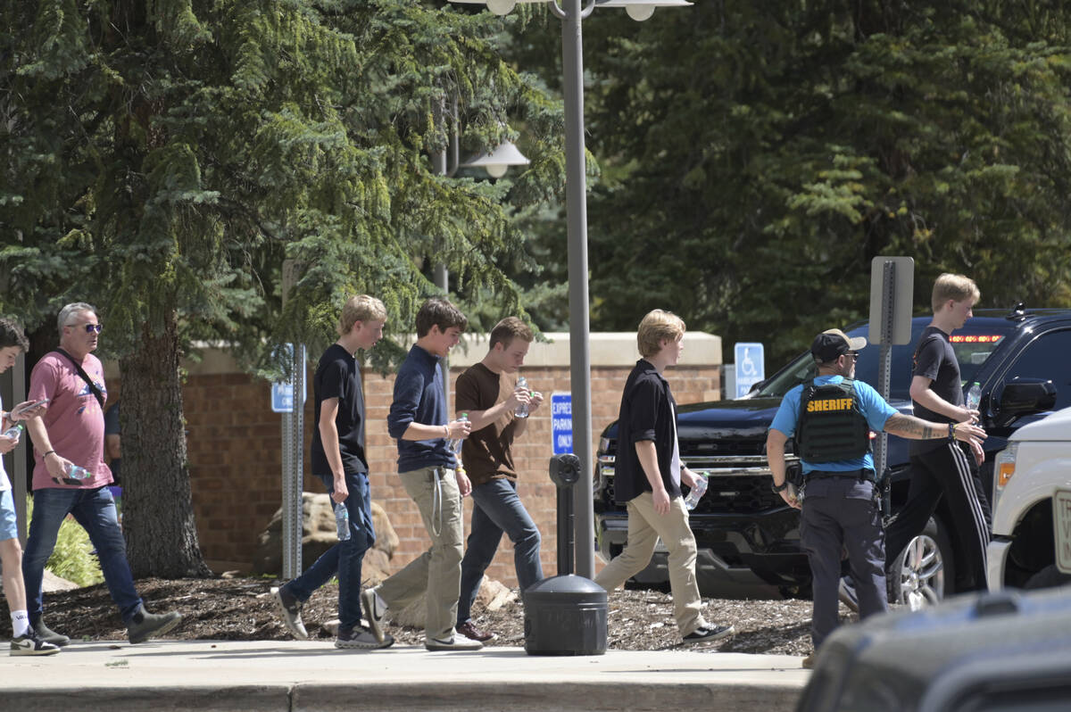 Students walk to board a bus amid heavy police presence at the Evergreen Library after a shooti ...