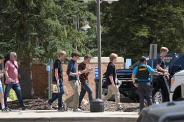 Students walk to board a bus amid heavy police presence at the Evergreen Library after a shooti ...