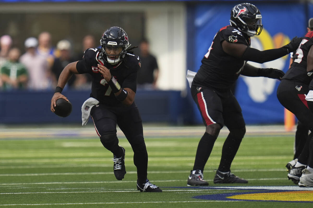 Houston Texans quarterback C.J. Stroud, left, scrambles against the Los Angeles Rams during the ...
