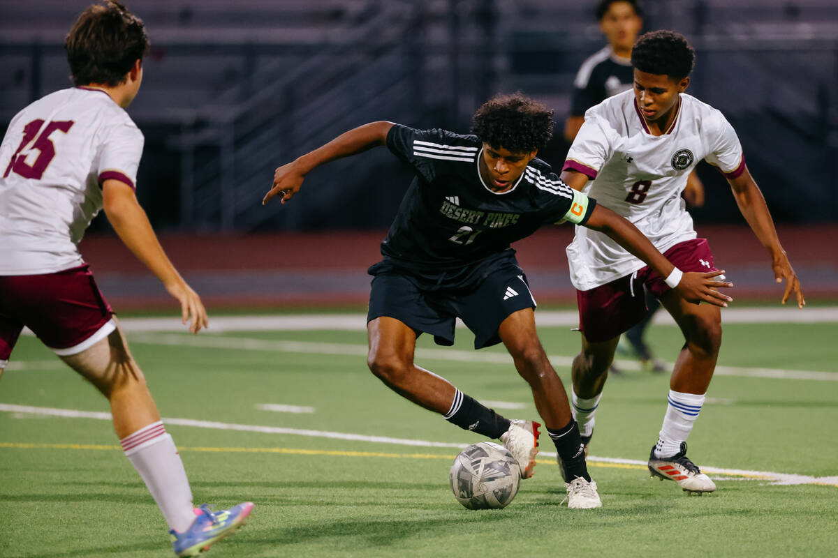 Desert Pines defender Thomas Figueroa (21) pivots the ball away from Faith Lutheran defender Is ...
