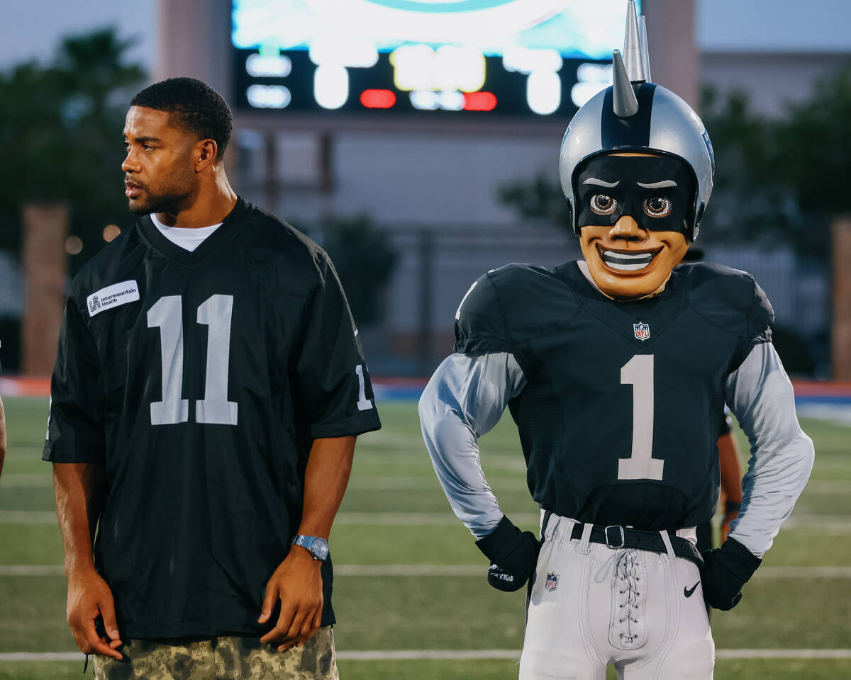 Raiders safety Jeremy Chinn, left, and mascot Raider Rusher, right, stand in the middle of the ...