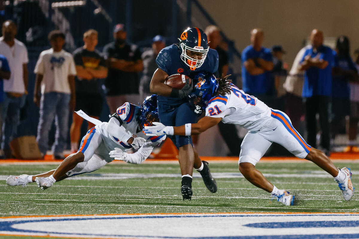 Bishop Gorman running back Noah Cole (20) darts between two tackling East St. Louis players, de ...